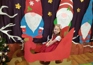 Dziewczynka siedzi w saniach Mikołaja